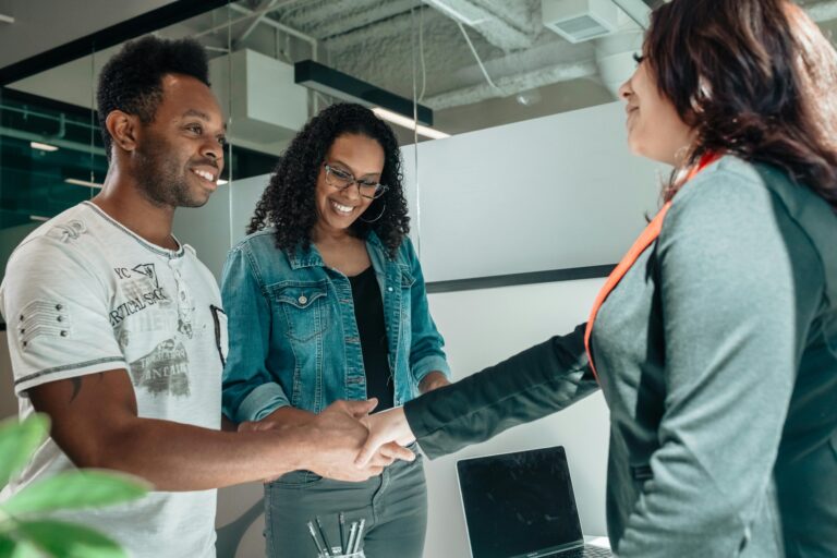 couple shaking hands with a worker in an office